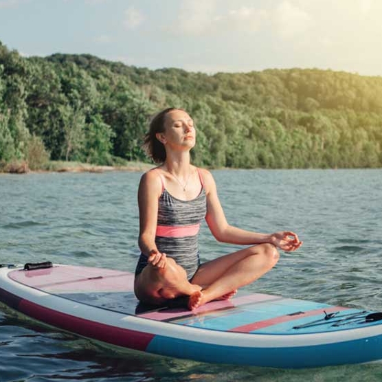 jeune femme méditant sur une planche à voile debout