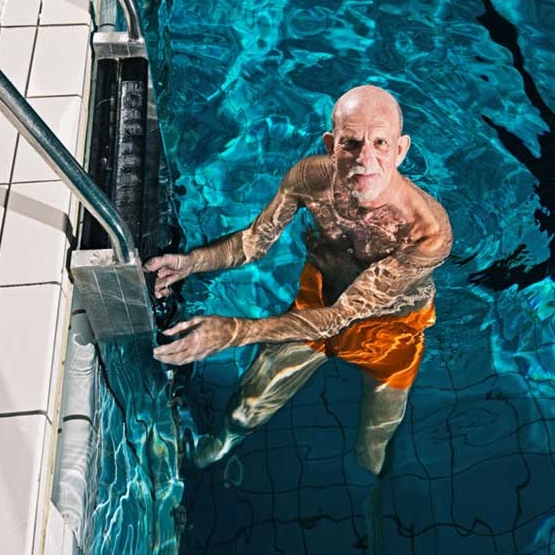 homme âgé à l’échelle dans une piscine