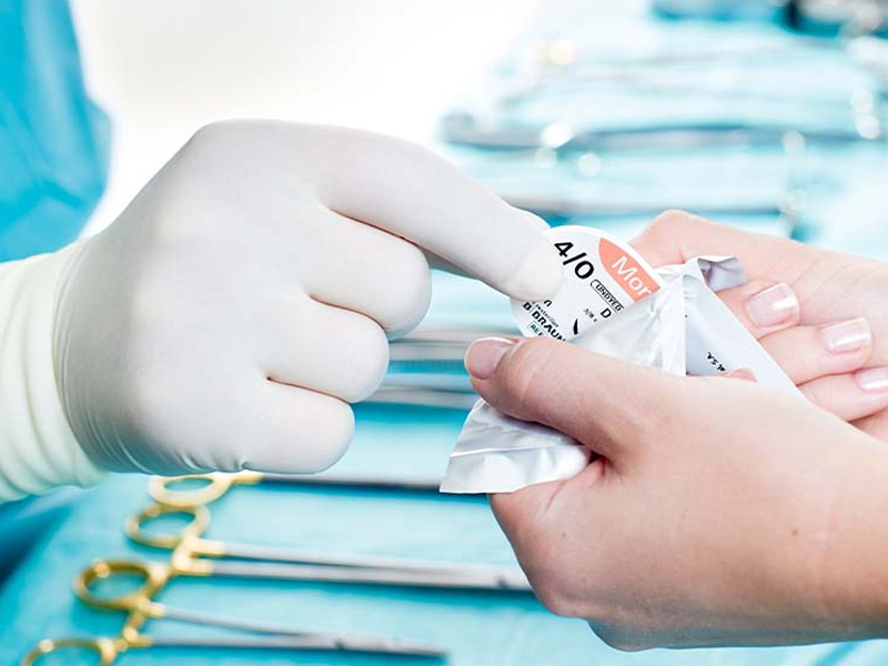 main de chirurgien au bloc opératoire avec instrumentation et sutures