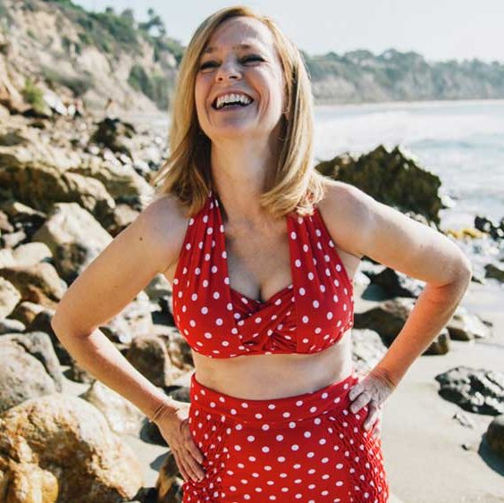 femme à la plage riant dans un bikini rouge à pois blancs